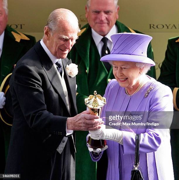 Prince Philip, Duke of Edinburgh presents Queen Elizabeth II with the winning owner's trophy after her horse 'Estimate' won The Queen's Vase horse...