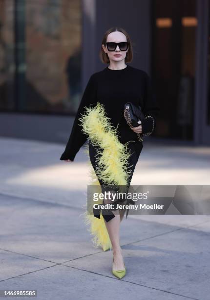 Katya Bychkova seen wearing Louis Vuitton black sunglasses, The Attico black knit sweater with yellow feather boa detail, Coperni black short pants...