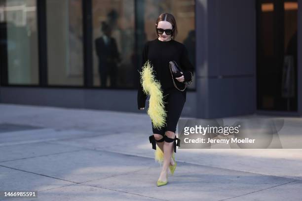 Katya Bychkova seen wearing Louis Vuitton black sunglasses, The Attico black knit sweater with yellow feather boa detail, Coperni black short pants...