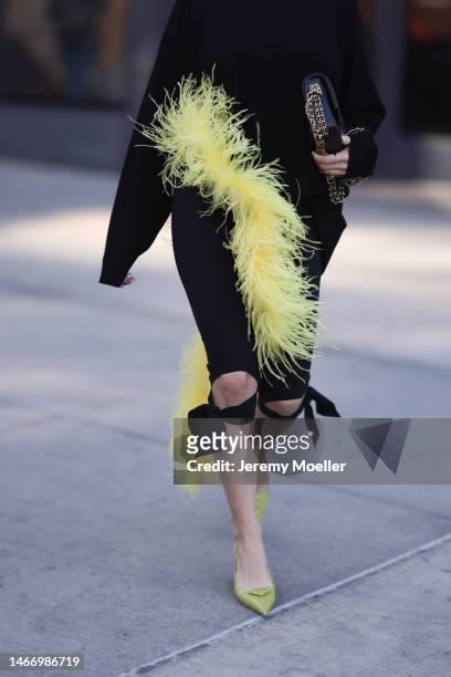 Katya Bychkova seen wearing The Attico black knit sweater with yellow feather boa detail, Coperni black short pants with ribbons, Chanel black...