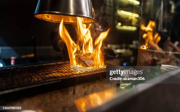 chef in action using a charcoal barbecue to cook wagyu beef - restaurant fire stock pictures, royalty-free photos & images