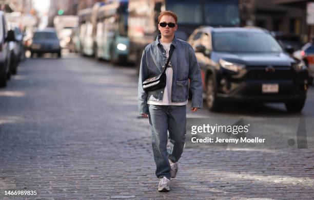 Erik Scholz seen wearing Prada Symbole black sunglasses, Wrstbhvr white cotton printed t-shirt, Zara blue denim two-piece with long jeans pants and...