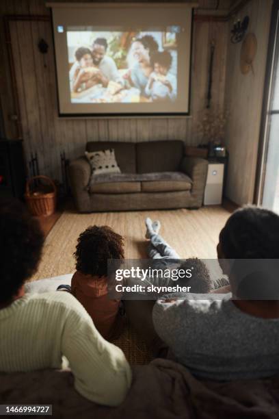 rear view of black family watching a movie at home. - living projector stockfoto's en -beelden