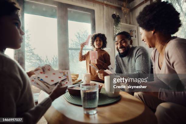 glückliche afroamerikanische familie, die zu hause karten spielt. - card game mature people stock-fotos und bilder
