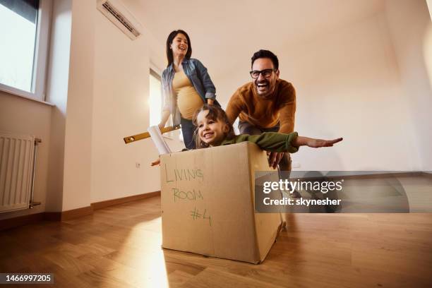 glückliche schwangere familie, die spaß in einer neuen wohnung hat. - familie eigenheim stock-fotos und bilder