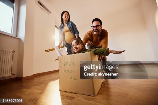 Happy pregnant family having fun in a new apartment.