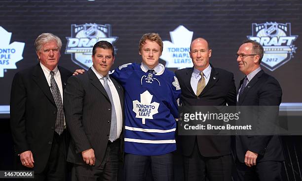 Morgan Rielly, fifth overall pick by the Toronto Maple Leafs, poses on stage with general manager Brian Burke and team representatives during Round...