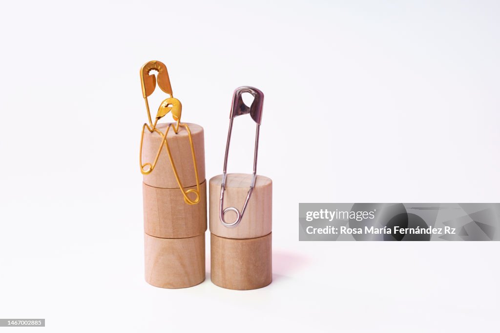 Three Safety Pins in Gold and Silver Metal, Representing a Multiracial Family Sitting on Wooden Blocks