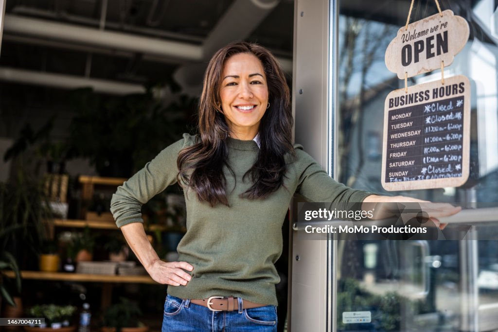 Portrait of proud female flower shop owner in front of open sign
