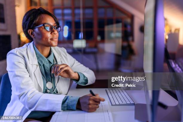 giovane bella dottoressa che lavora fino a tarda notte in ufficio - cartella clinica elettronica foto e immagini stock