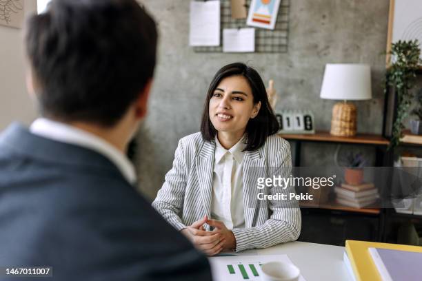 young beautiful businesswoman talking with her colleague in the office - face to face interview stock pictures, royalty-free photos & images
