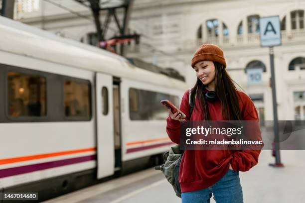 young hipster asian woman using smart phone at the rail station - railroad station imagens e fotografias de stock