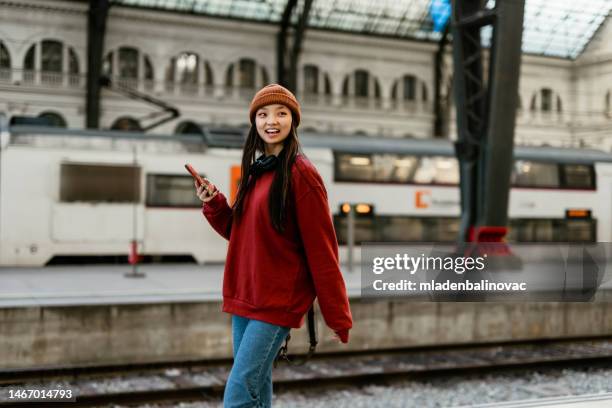 young hipster asian woman using smart phone at the rail station - subway station stock pictures, royalty-free photos & images