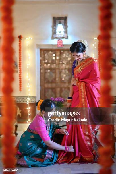indian woman helping another woman to fix her sari pleats while getting ready for the traditional festival - pleated stock pictures, royalty-free photos & images