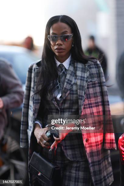 Jan-Michael Quammie wears a grey/blue checkered blazer, matching vest, matching suit pants, silk grey/white/black tie, a white blouse and a black...