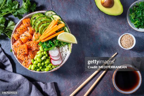 salmon poke bowl on dark gray with edamame, wakame seaweed, avocado - pokes stock pictures, royalty-free photos & images