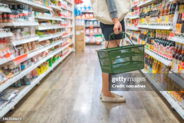 asian woman holding a shopping basket, grocery shopping in supermarket. healthy eating lifestyle shopping. pesticide safe food and vegetable selection for life. - shopping list trolley stock pictures, royalty-free photos & images