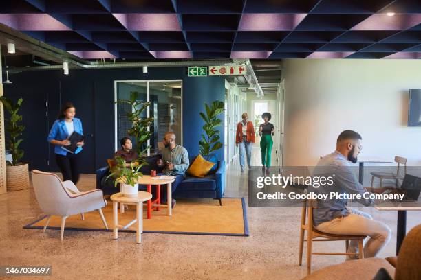 group of diverse businesspeople working in a busy office lounge - co working space stockfoto's en -beelden