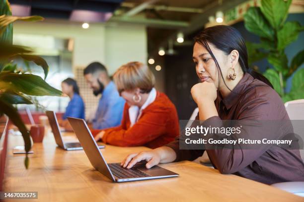 diverse businesspeople working in a row at an office table - hot desking stock pictures, royalty-free photos & images