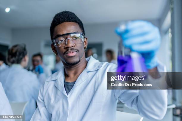 un étudiant examine un liquide en laboratoire - chimie photos et images de collection