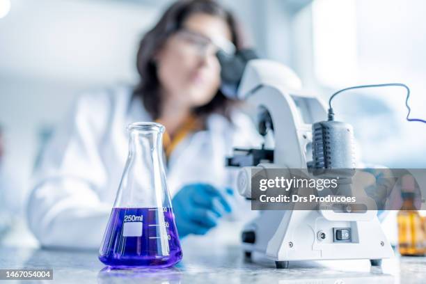 adult female student analyzing liquid under microscope - conical flask stock pictures, royalty-free photos & images