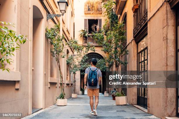 young man exploring narrow alleys of barcelona, spain - vieille ville photos et images de collection