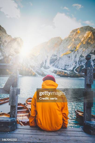 young man enjoys nature on the coast of braies lake, dolomites, italy - yellow jacket stockfoto's en -beelden