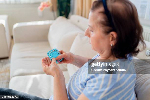 menopausal mature woman checking patient information leaflet for her medicine - hrt pill stockfoto's en -beelden