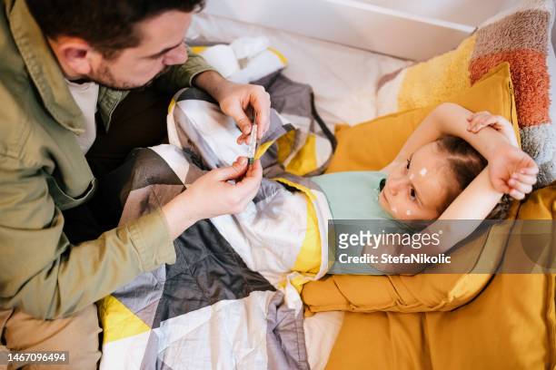 padre tomando la temperatura de la hija pequeña - varicela fotografías e imágenes de stock