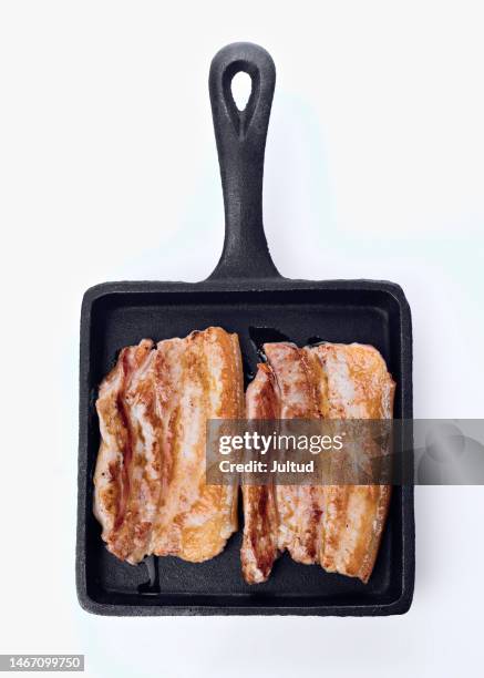top view of two pork belly fillets roasted in a black iron skillet - pork belly stock pictures, royalty-free photos & images