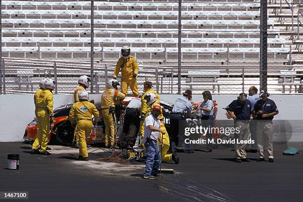 And firefighters attend to Adam Petty and his car after Petty spun-out and crashed into a concrete barrier during practice for the Busch 200, part of...