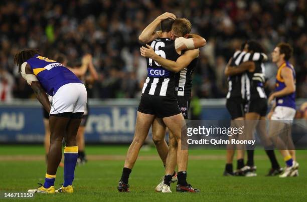 Nathan Brown and Ben Reid of the Magpies celebrates winning as Nic Naitanui of the Eagles looks dejected during the round 13 AFL match between the...