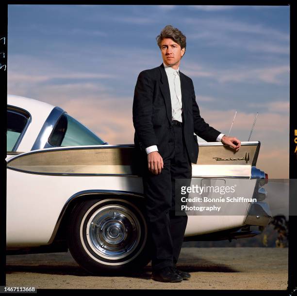 Director David Lynch stands outdoors in front of Packard vehicle in Los Angeles in 1986.