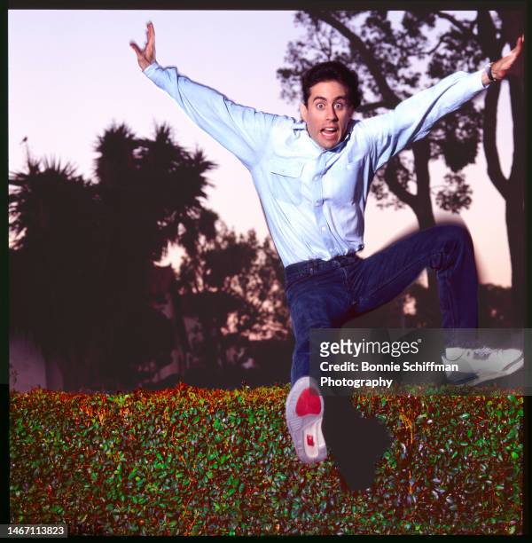 Comedian Jerry Seinfeld leaps over a green hedge and makes a face in Los Angeles in 1989.