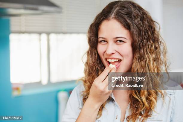 beautiful young long-haired woman smiles at the camera as she puts a healthy piece of apple into her mouth - chewing with mouth open stock pictures, royalty-free photos & images