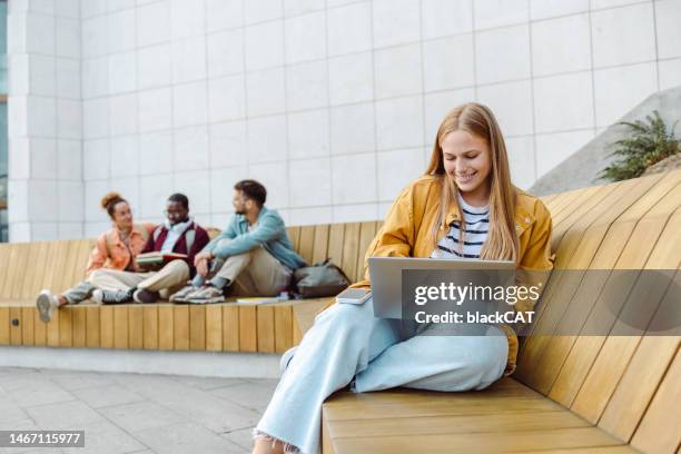 junge studentin mit laptop auf der bank - bank student stock-fotos und bilder