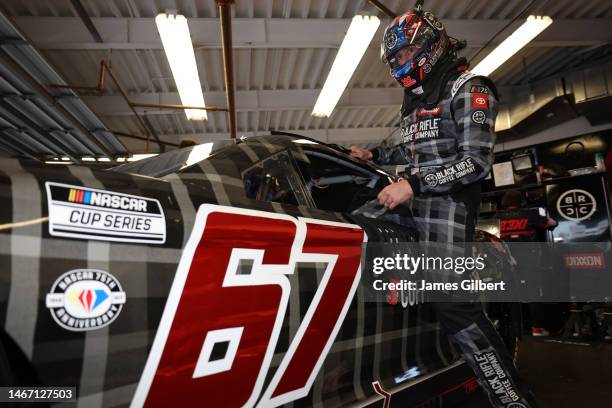 Travis Pastrana, driver of the Black Rifle Coffee Toyota, enters in his car in the garage area during practice for the NASCAR Cup Series 65th Annual...