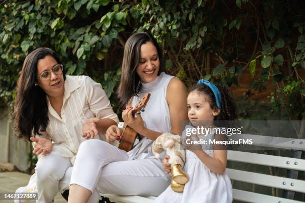 family singing and playing ukulele - nichtje stockfoto's en -beelden