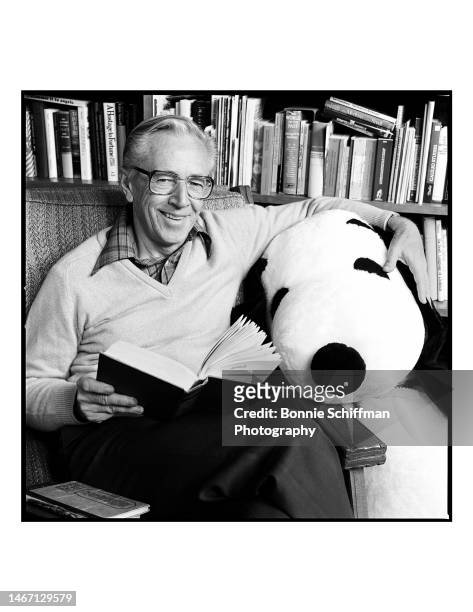 Peanuts creator Charles M Schulz sits with an open book and hugs a large stuffed Snoopy in Los Angeles in 1985