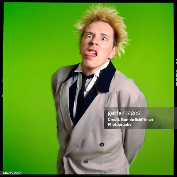 Musician John Lydon from The Sex Pistols sticks out his tongue in front of green backdrop in Los Angeles in 1989.