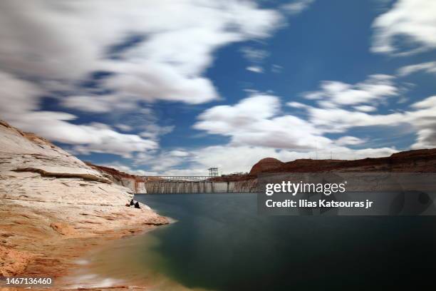 tourists at the banks of large lake glenn canyon, dam in background, under cloudy sky - glen canyon dam stock pictures, royalty-free photos & images