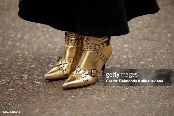 Guest wearing black skirt and gold shoes outside Fashion east fashion show during London Fashion Week February 2023 on February 17, 2023 in London,...