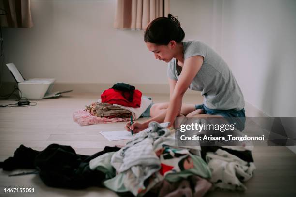 a woman is putting her clothes to be donated. - decluttering stock pictures, royalty-free photos & images