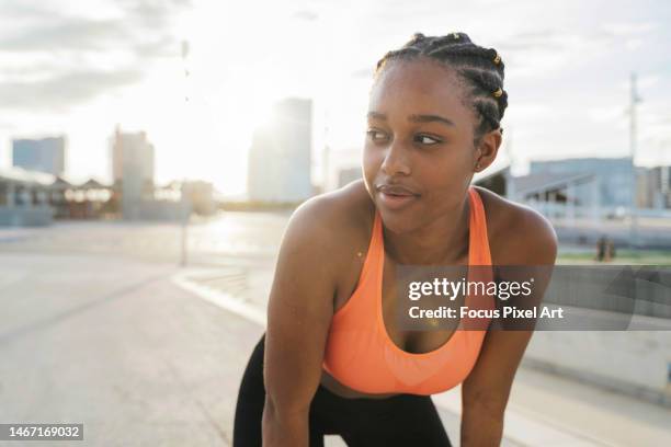 young athlete woman with sweat on her face exercising outside the city. effort and youth concept. - beha stockfoto's en -beelden
