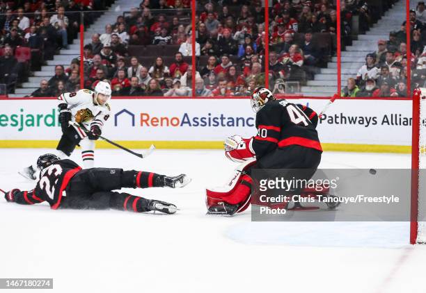 Patrick Kane of the Chicago Blackhawks scores against Mads Sogaard of the Ottawa Senators as his teammate Travis Hamonic looks on during the third...