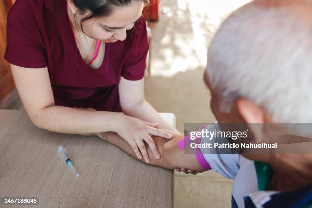 rural nurse looking for the vein in the arm of a senior male patient - blood donation stock pictures, royalty-free photos & images