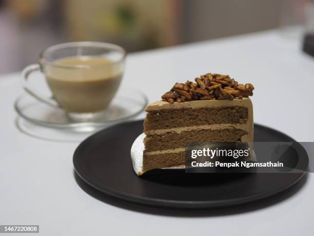 hot coffee in white cup and caramel almond coffee cake in black plate - torta a strati foto e immagini stock