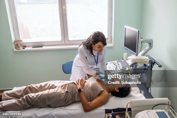 african american woman examining her thyroid with ultrasound - thyroid cancer stock pictures, royalty-free photos & images