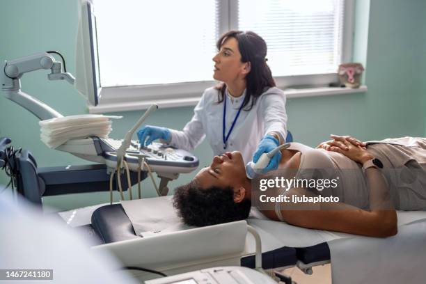 ultrasound diagnosis of thyroid gland in young woman in clinic - echoscopist stockfoto's en -beelden
