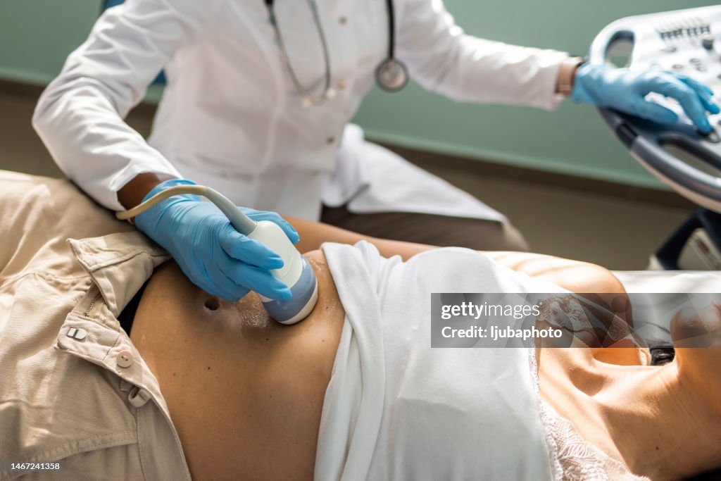 Doctor examining mature woman with ultrasound scanner device